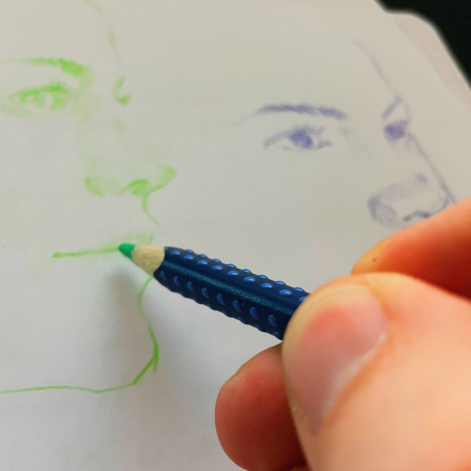 A portrait of a woman is drawn by a hand holding a green crayon.